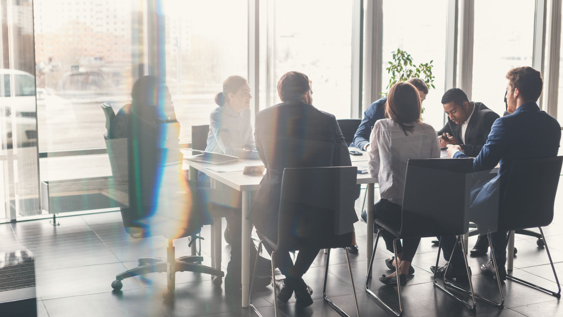 Group of seven people in a small meeting room as seen through the meeting room window