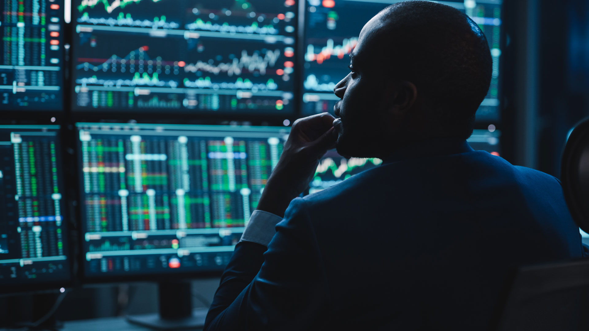 View from behind a man looking at stock market screens