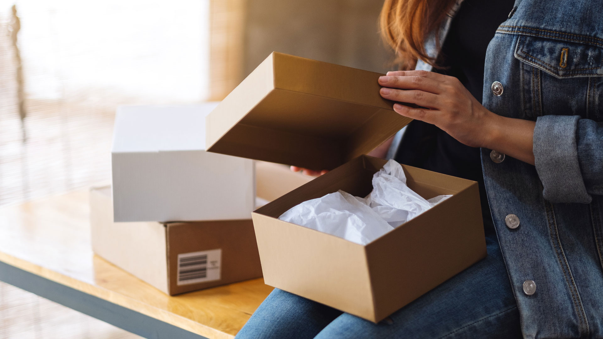 Close up of woman opening box with lid to reveal tissue paper inside