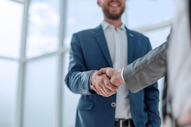 Two business men shaking hands in office setting