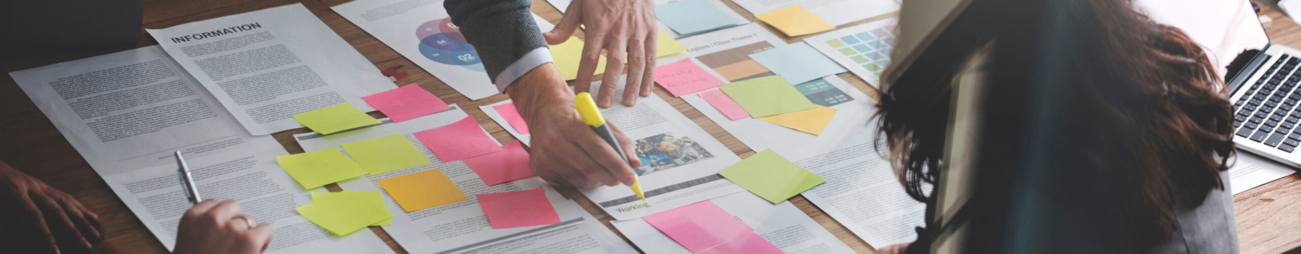 Small group of people working at table with many post-it notes on paperwork