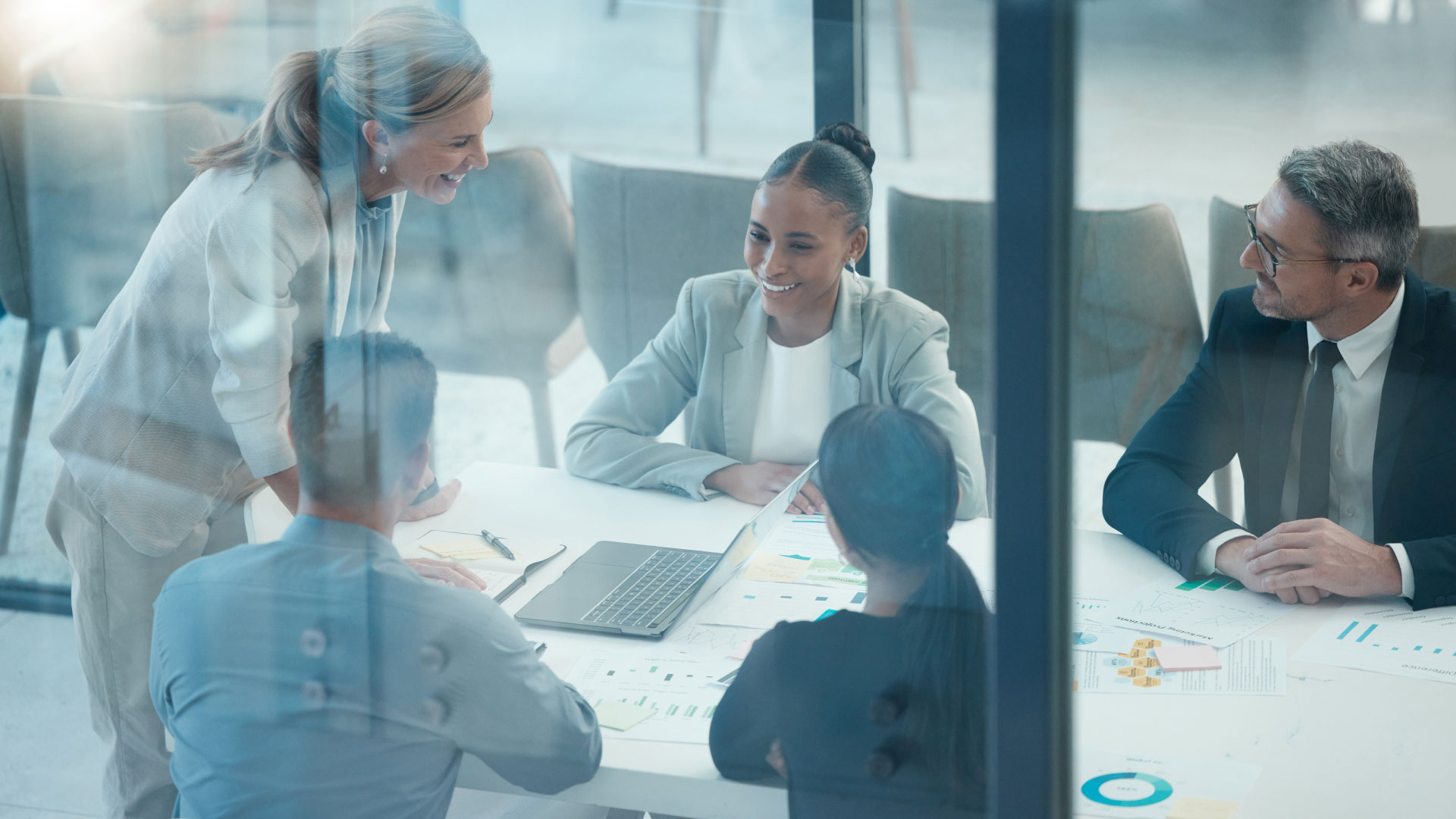 Five people meeting in a conference room around a laptop