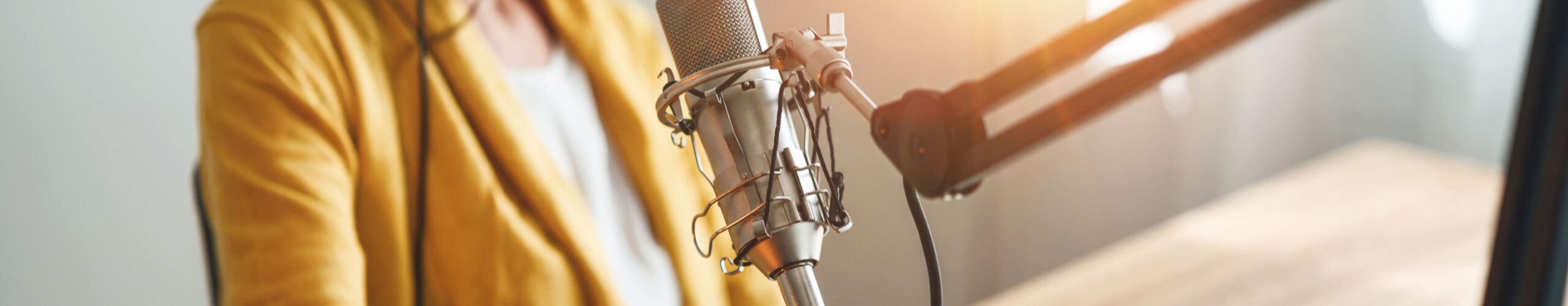 Woman wearing yellow blazer speaking into professional microphone set up