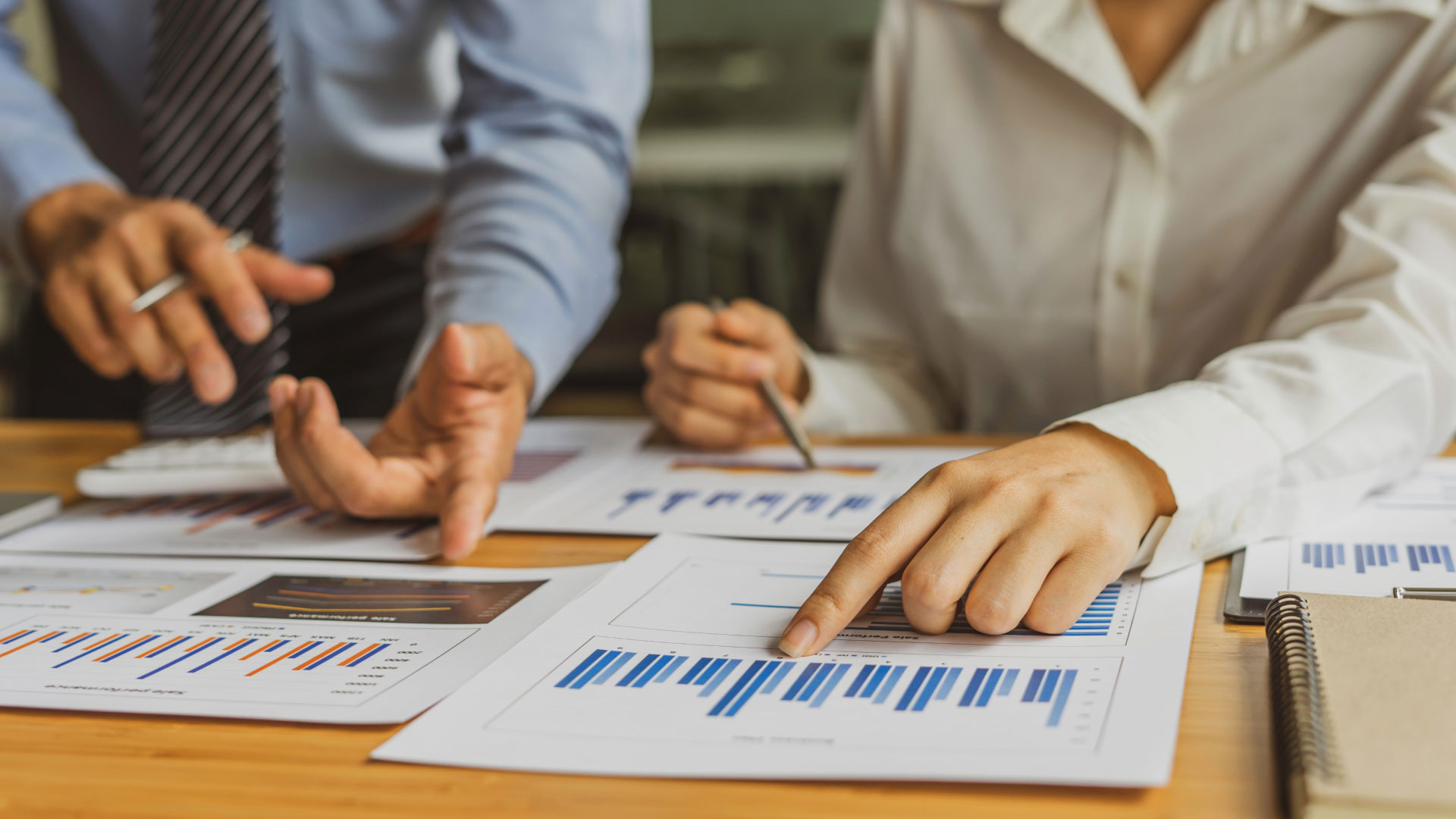 Close up of a male and female colleague reviewing chart print outs