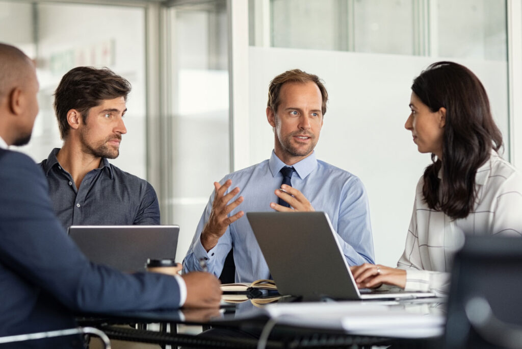 Group of four people in small meeting with laptops