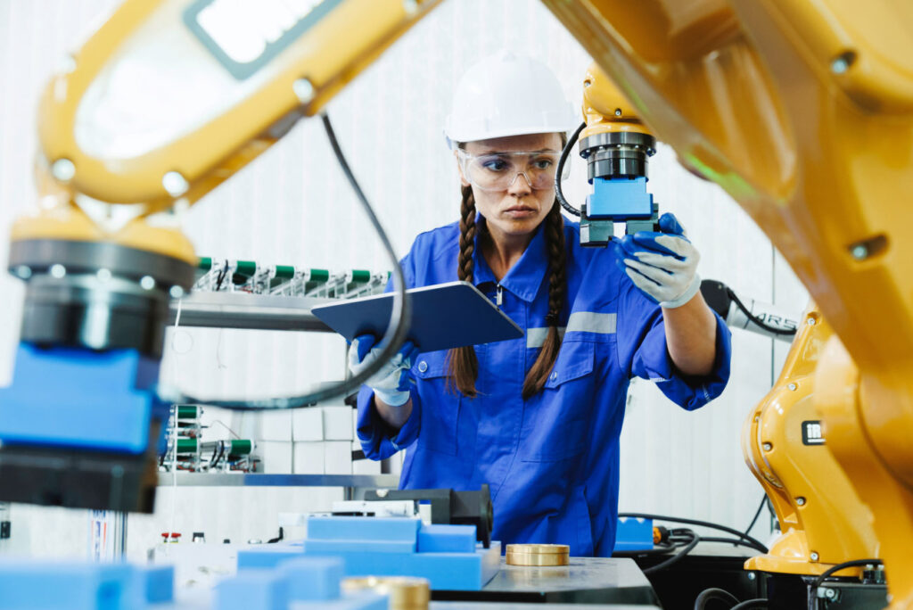 Female wearing a white hard had holding a tablet while inspecting machinery