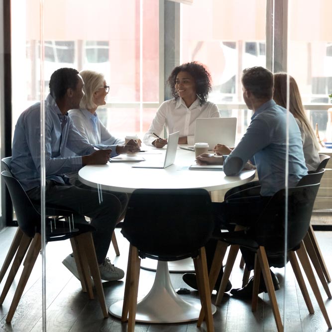 African American boss with employees sitting at desk in boardroom