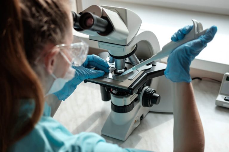 Female lab tech looking through microscope