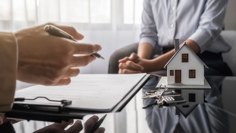 Two men sitting across from each other discussing paperwork for home mortgage