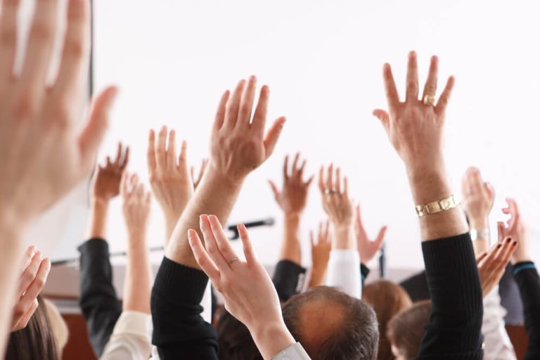 people raising their hands voting in conference room