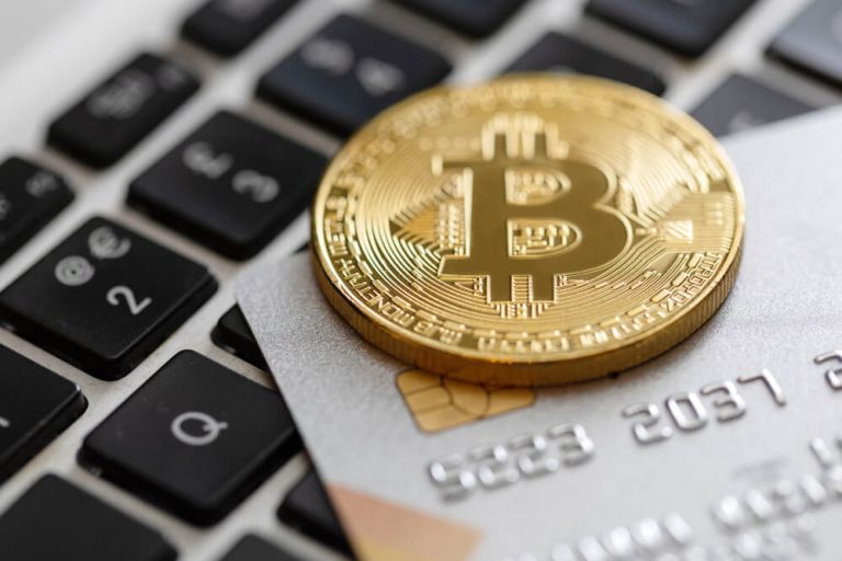 Close up shot of bitcoin lying on top of credit card on computer keyboard