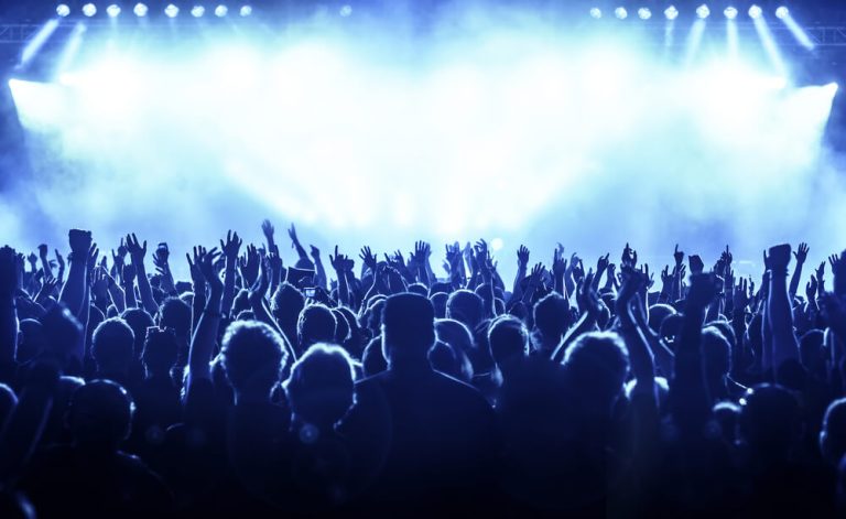 cheering crowd at rock concert in front of bright lights