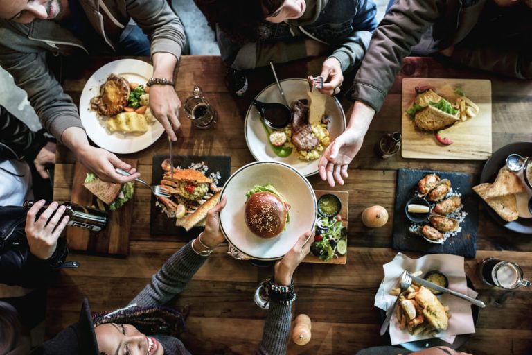 Overhead image of restaurant table with patrons passing plates around