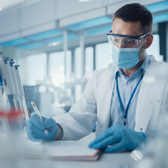 Scientist wearing face mask and analyzing chemicals in medical research laboratory