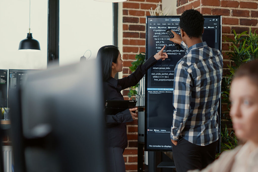 Male and female colleague discussing IT plan on white board