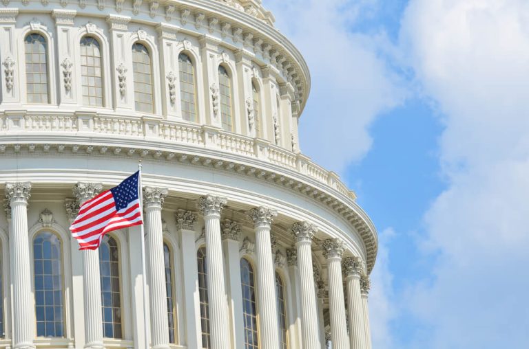 Close up photo of the US Capitol building with American flag