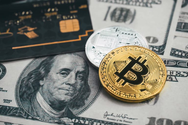 bitcoin coin close up next to US dollar bill and credit card