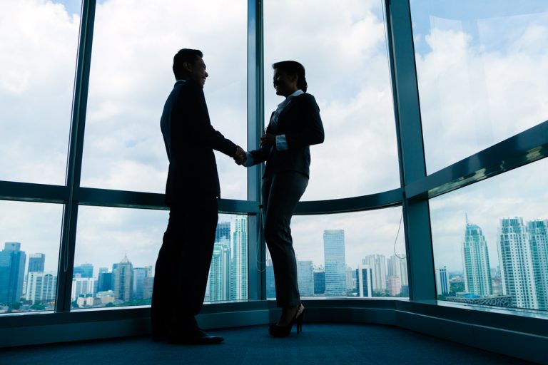 Business people handshake to seal deal in front of city skyline