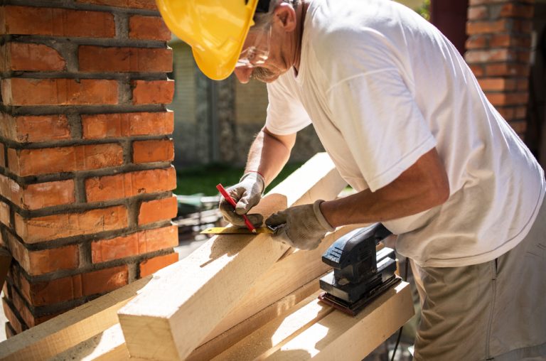 Man sanding a wooden beam