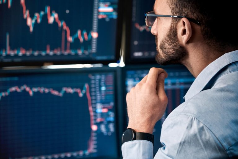 investor looking at computer screens with stock charts