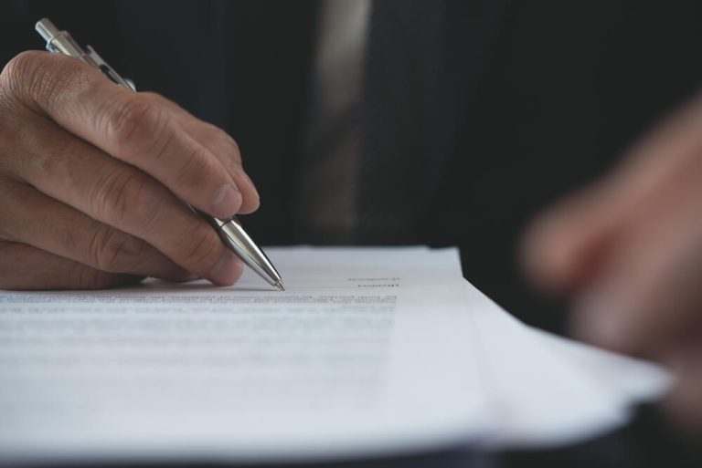 Close up on man in suit signing official document