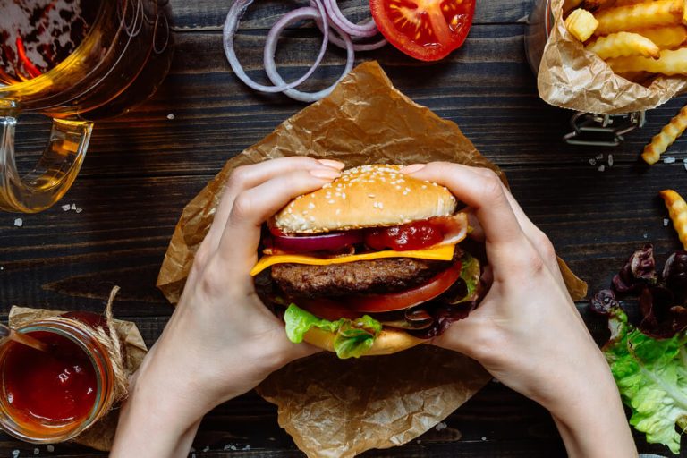 Hands holding cheeseburger at restaurant table