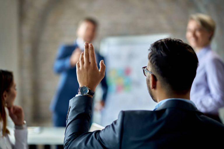 businessman raising hand to ask presenter a question