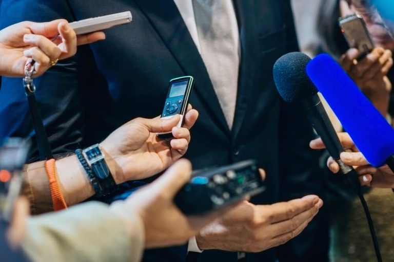 Interviewers holding microphones to business executive at press conference