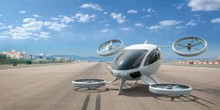 white electric powered Vertical Take Off and Landing eVTOL aircraft with four rotors parked on runway of an airport