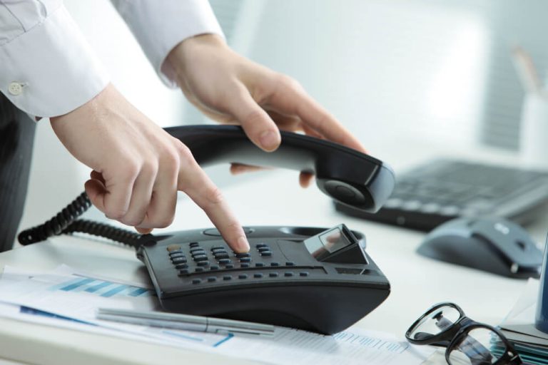 close up of businessman dialing on office phone to make call