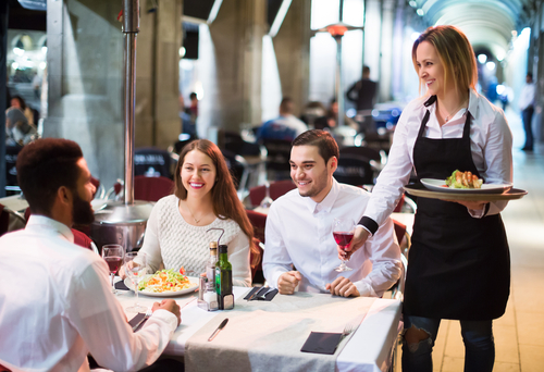 people at table in restaurant with server